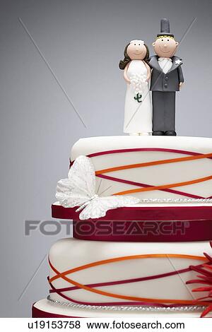 Stock Photo - Comical bride and groom figurines on top of wedding cake. Fotosearch