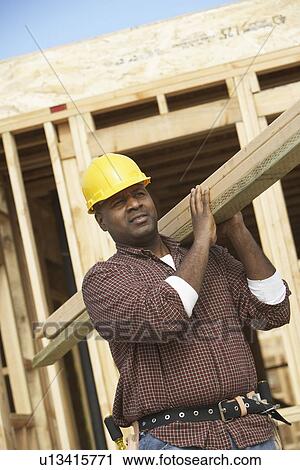 Stock Image - Construction Worker Carrying Lumber. Fotosearch