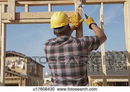 Stock Image - Construction Worker Working on Timber Frame. Fotosearch