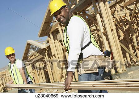 Construction workers carrying boards at construction Site View Large Photo Image Stock Photo - Construction workers carrying boards at construction Site. Fotosearch