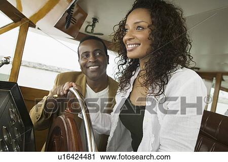Stock Image - Couple at steering wheel on yacht. Fotosearch