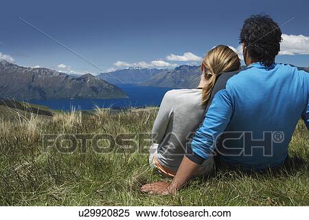 Couple cuddling looking over lake and hills back view View Large Photo Image Stock Photography - Couple cuddling looking over lake and hills back view. Fotosearch