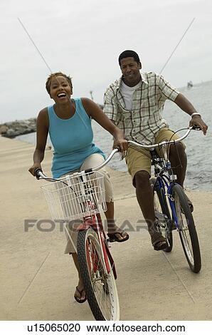 Couple cycling on beach smiling View Large Photo Image Stock Image - Couple cycling on beach smiling. Fotosearch