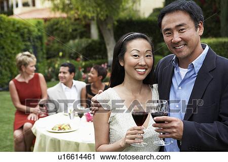 Stock Image - Couple drinking wine at garden party. Fotosearch