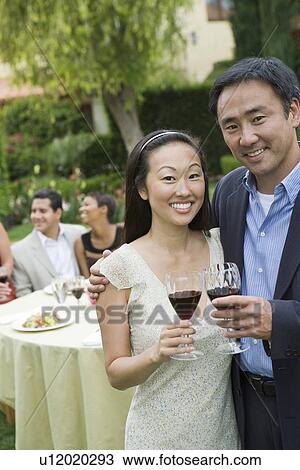 Stock Image - Couple drinking wine with friends outdoors. Fotosearch