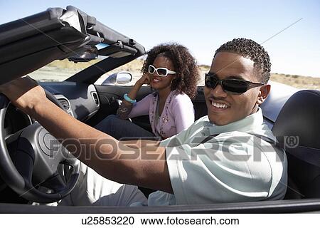 Couple driving convertible on desert road View Large Photo Image Stock Image - Couple driving convertible on desert road. Fotosearch