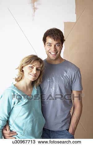 Couple embracing in front of partially painted wall portrait View Large Photo Image Stock Image - Couple embracing in front of partially painted wall portrait. Fotosearch