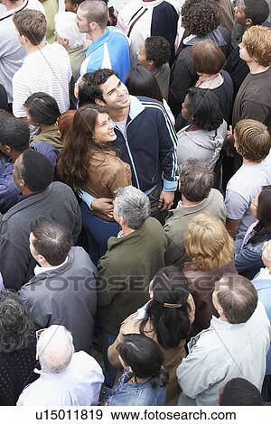 Stock Photo - Couple facing the other way to rest of crowd elevated view. Fotosearch