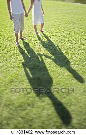 Couple holding hands walking on grass low section View Large Photo Image Stock Image - Couple holding hands walking on grass low section. Fotosearch