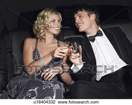 Stock Image - Couple in back of car drinking champagne. Fotosearch