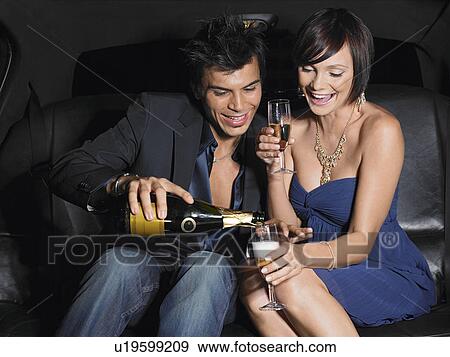 Stock Photo - Couple in back of limousine drinking champagne. Fotosearch