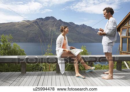 Stock Photo - Couple in pajamas on balcony overlooking a mountain lake. Fotosearch