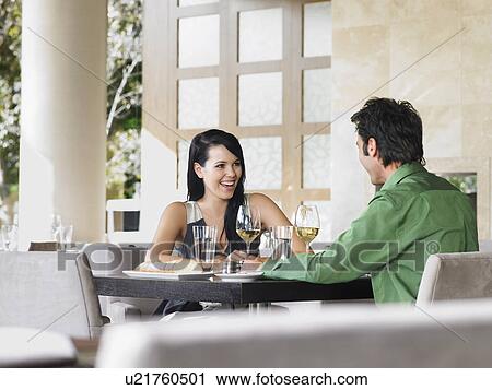 Couple laughing over wine at outdoor restaurant View Large Photo Image Stock Image - Couple laughing over wine at outdoor restaurant. Fotosearch