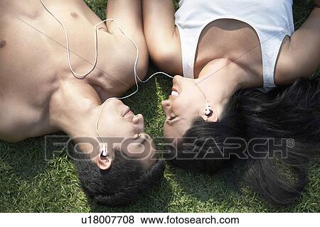 Couple listening to mp3 player lying down on grass view from above View Large Photo Image Stock Photo - Couple listening to mp3 player lying down on grass view from above. Fotosearch