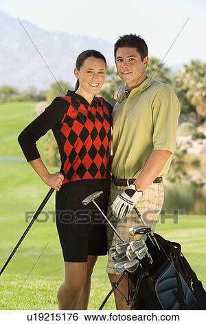 Couple of golfers standing together on golf course (portrait) View Large Photo Image Stock Photograph - Couple of golfers standing together on golf course (portrait). Fotosearch