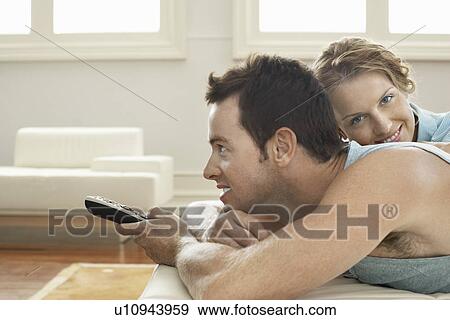 Couple on bed relaxing together man holding remote control View Large Photo Image Stock Photo - Couple on bed relaxing together man holding remote control. Fotosearch