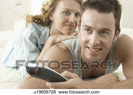 Stock Photo - Couple on bed relaxing together man holding remote control. Fotosearch