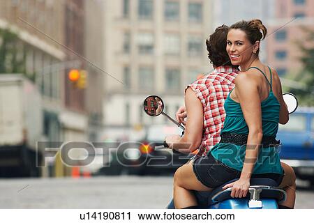Couple riding on moped in street View Large Photo Image Stock Image - Couple riding on moped in street. Fotosearch