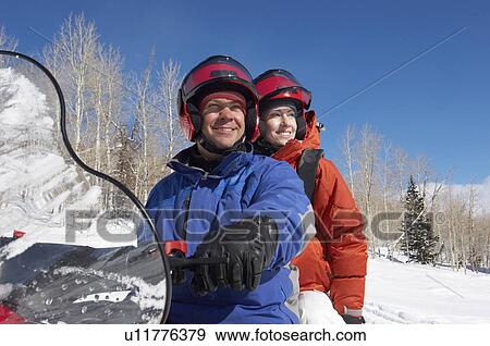 Stock Photo - Couple Sitting on Snowmobile in snow. Fotosearch