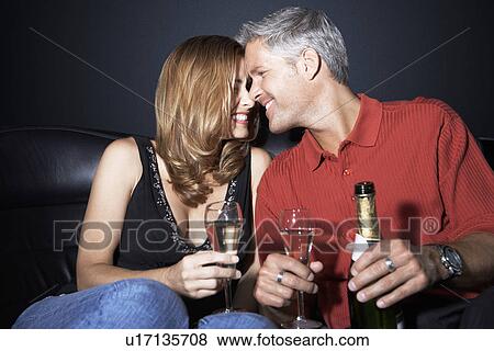 Stock Photo - Couple sitting rubbing noses holding champagne glasses. Fotosearch