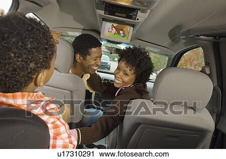 Stock Image - Couple smiling at young son in car. Fotosearch