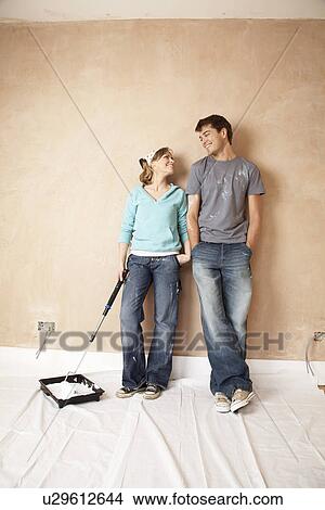 Couple standing with paint roller in unrenovated room View Large Photo Image Picture - Couple standing with paint roller in unrenovated room. Fotosearch