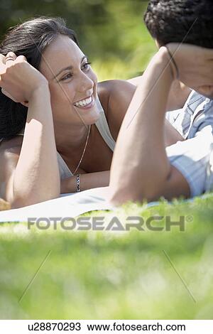 Couple talking face to face lying on park lawn View Large Photo Image Stock Image - Couple talking face to face lying on park lawn. Fotosearch