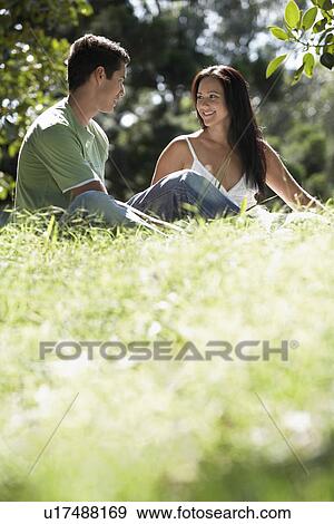 Stock Photo - Couple talking together other sitting on grass ground view. Fotosearch