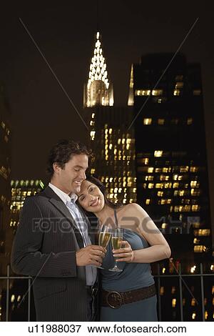 Couple Toasting with Champagne against New York Night Skyline View Large Photo Image Stock Photo - Couple Toasting with Champagne against New York Night Skyline. Fotosearch