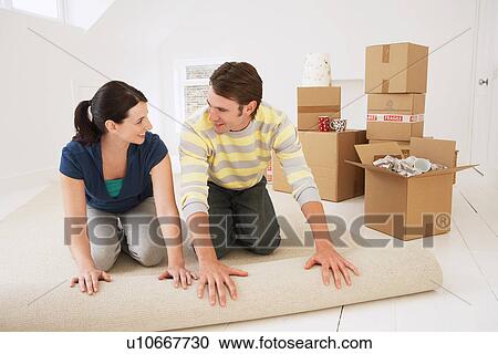 Couple unrolling carpet in new home View Large Photo Image Stock Image - Couple unrolling carpet in new home. Fotosearch