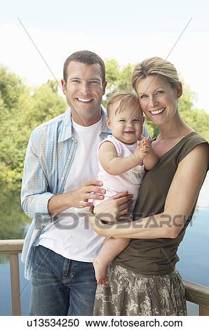 Couple with child standing by lake half length View Large Photo Image Stock Image - Couple with child standing by lake half length. Fotosearch