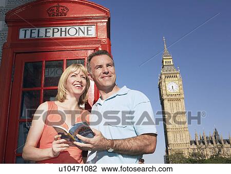 Couple with guidebook standing by London phone booth View Large Photo Image Stock Image - Couple with guidebook standing by London phone booth. Fotosearch