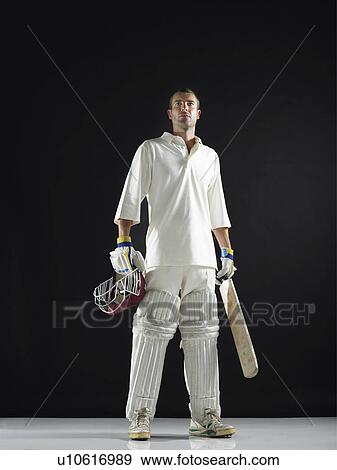 Stock Photo - Cricket player standing holding cricket bat low angle view. Fotosearch