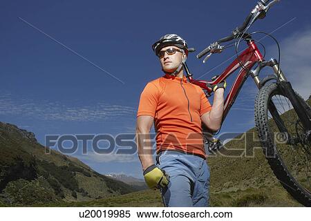 Cyclist carrying bike in countryside View Large Photo Image Stock Photography - Cyclist carrying bike in countryside. Fotosearch