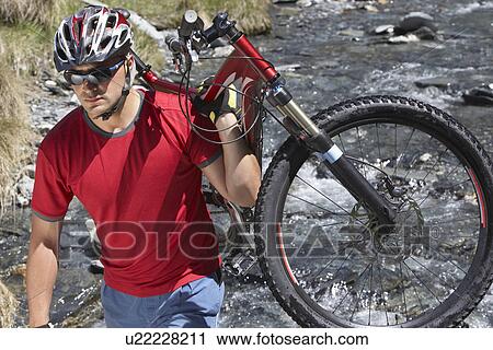 Cyclist carrying bike in river View Large Photo Image Stock Image - Cyclist carrying bike in river. Fotosearch