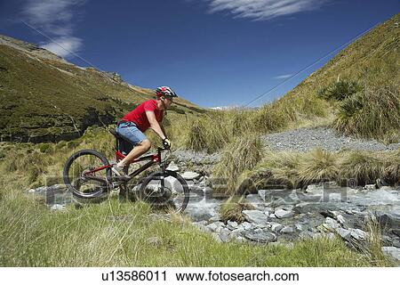 Cyclist riding through rocky field View Large Photo Image Stock Image - Cyclist riding through rocky field. Fotosearch