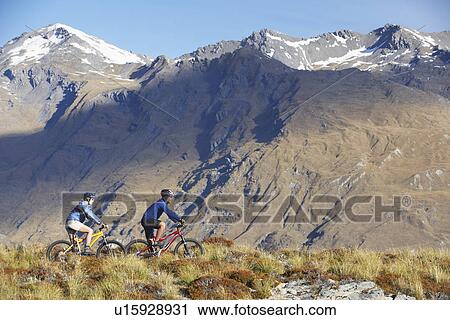 Cyclists riding past mountains View Large Photo Image Stock Image - Cyclists riding past mountains. Fotosearch