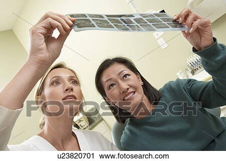 Dentist and patient examining X-ray in surgery View Large Photo Image Stock Image - Dentist and patient examining X-ray in surgery. Fotosearch