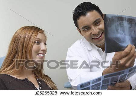 Stock Photo - Dentist and patient examining X-rays. Fotosearch