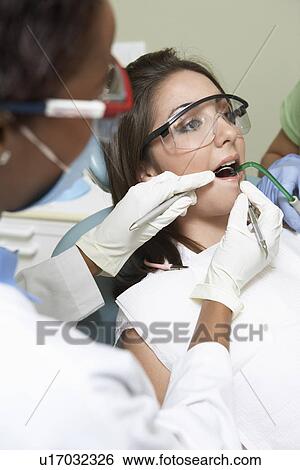 Stock Photograph - Dentist examining patients teeth in surgery. Fotosearch