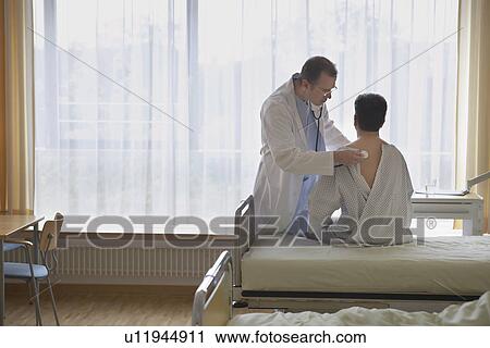 Doctor using stethoscope on back of patient in hospital room back view of patient View Large Photo Image Stock Image - Doctor using stethoscope on back of patient in hospital room back view of patient. Fotosearch