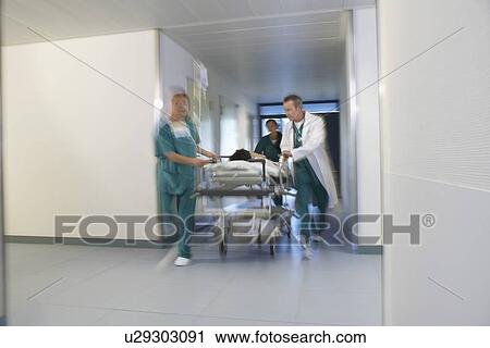 Doctors running Patient on gurney through hospital corridor motion blur View Large Photo Image Stock Image - Doctors running Patient on gurney through hospital corridor motion blur. Fotosearch