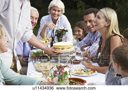 Stock Photograph - Family dining outdoors. Fotosearch