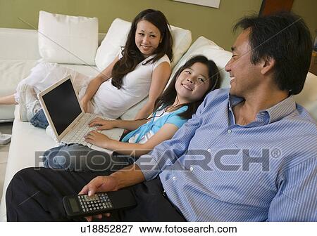 Family Relaxing on sofa in Living Room daughter with Laptop View Large Photo Image Stock Photo - Family Relaxing on sofa in Living Room daughter with Laptop. Fotosearch