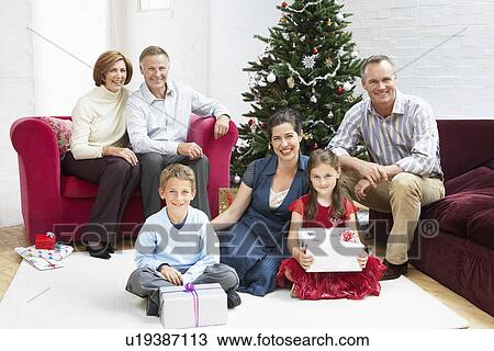 Family sitting by christmas tree in living room portrait View Large Photo Image Stock Image - Family sitting by christmas tree in living room portrait. Fotosearch