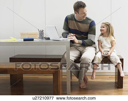 Stock Photo - Father and daughter using laptop and cell phone. Fotosearch
