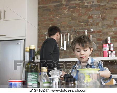Stock Photo - Father and son (3-4) in kitchen. Fotosearch