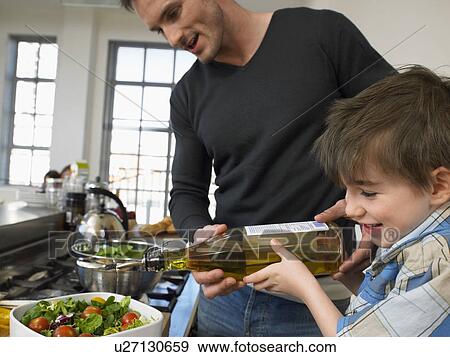 Stock Photo - Father and son (3-4) preparing salad in kitchen. Fotosearch