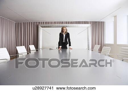 Stock Image - Female Business Executive standing in Boardroom. Fotosearch