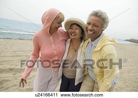 Female friends walking side by side on beach View Large Photo Image Stock Image - Female friends walking side by side on beach. Fotosearch